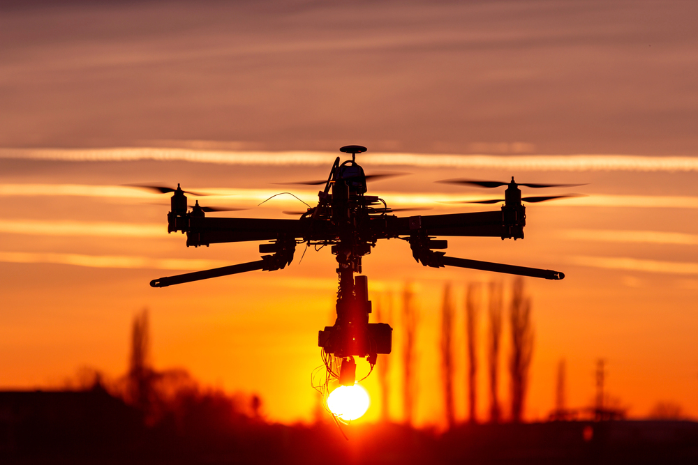 A professional drone in front of a sunset