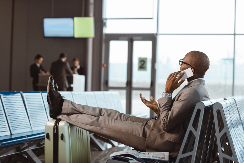 a businessman wearing a suit sitting in an airport while talking on a phone