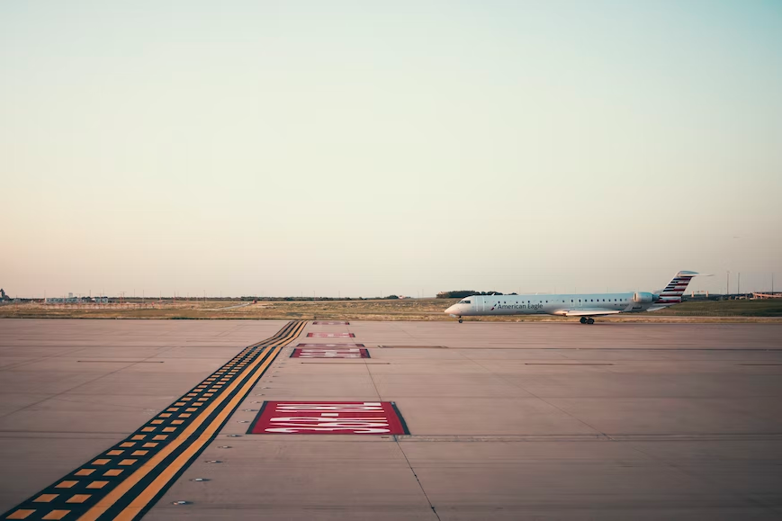 A white plane on an airport tarmac during the day.