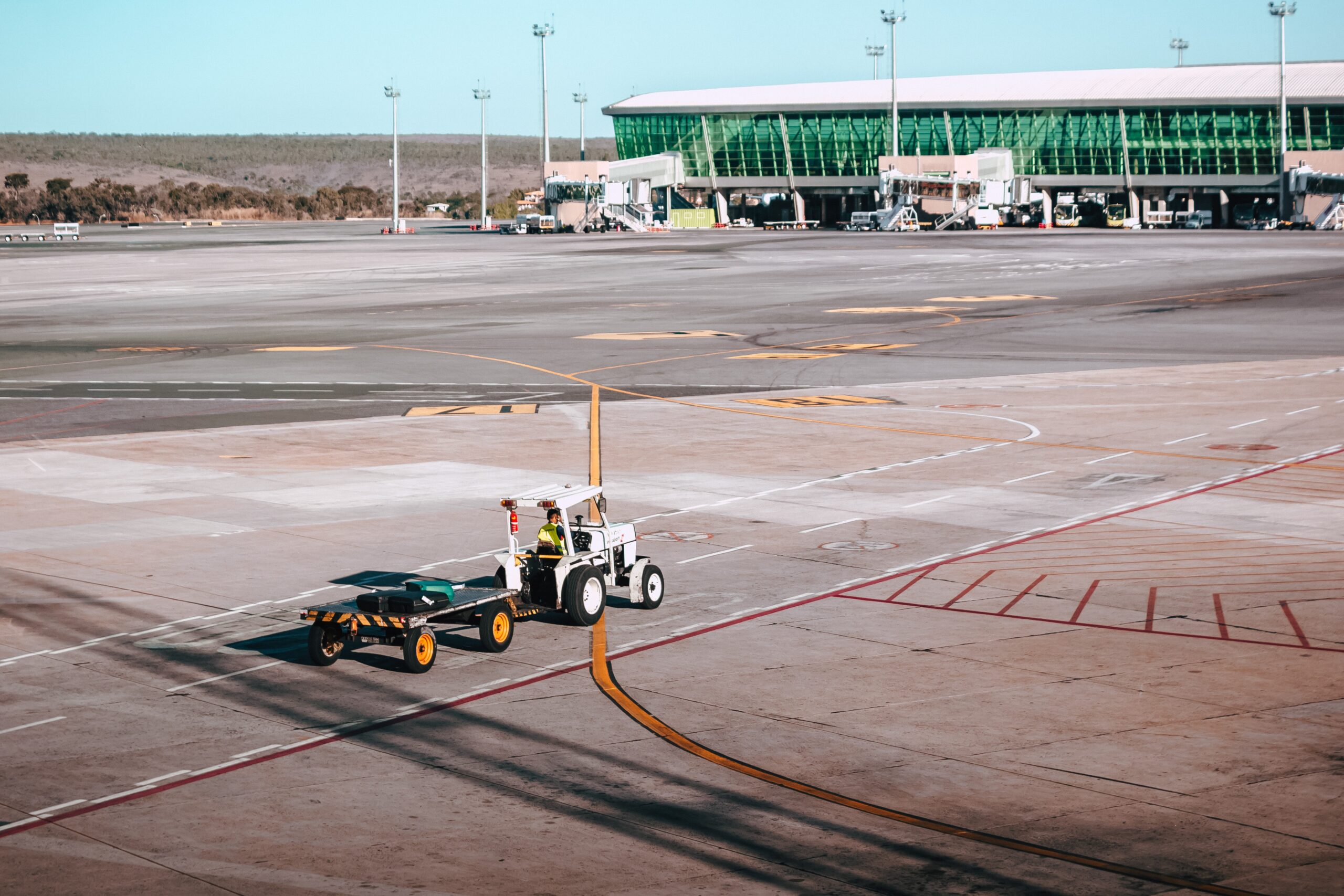 A small service vehicle hauls a trailer on an airport tarmac.