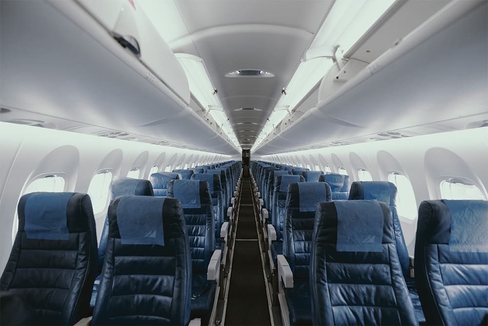 The interior of an empty airplane with blue seats.