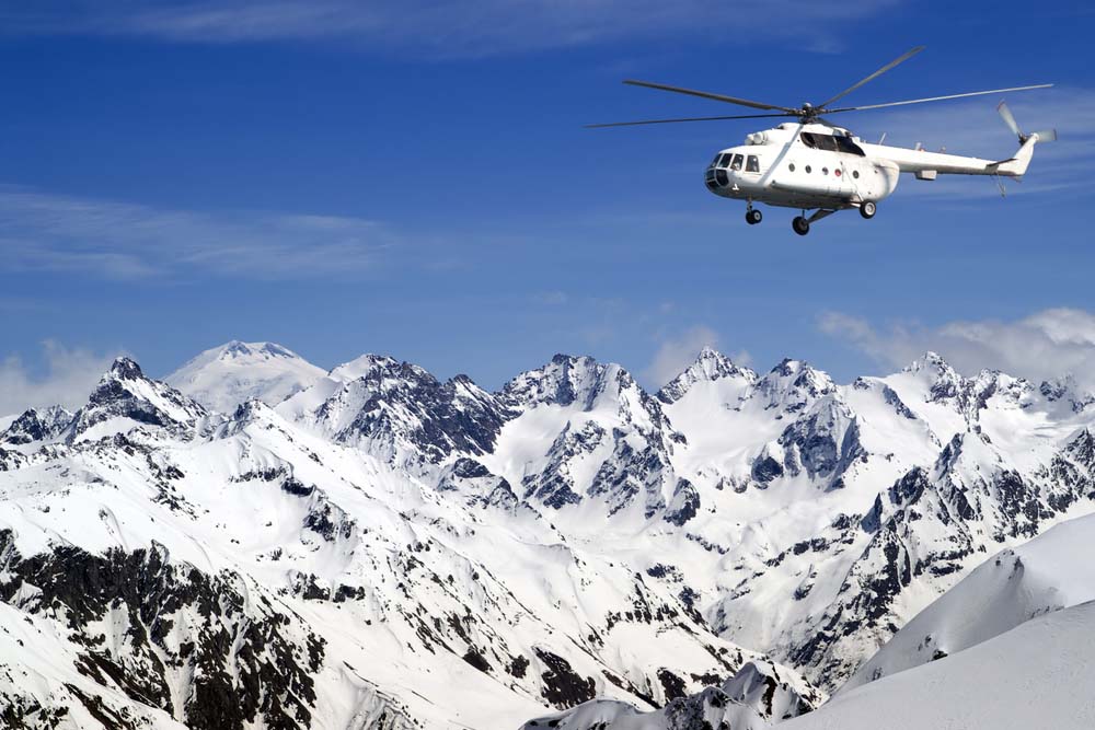 A helicopter flying above a snowy mountain.