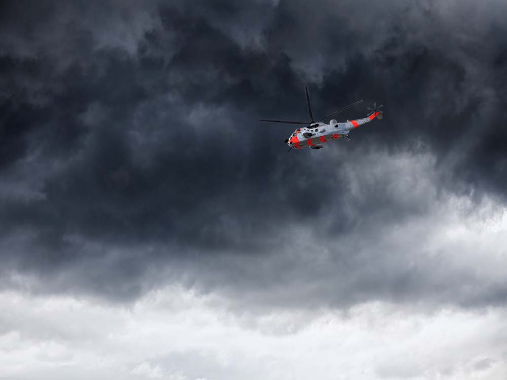 A helicopter flying against dark clouds.