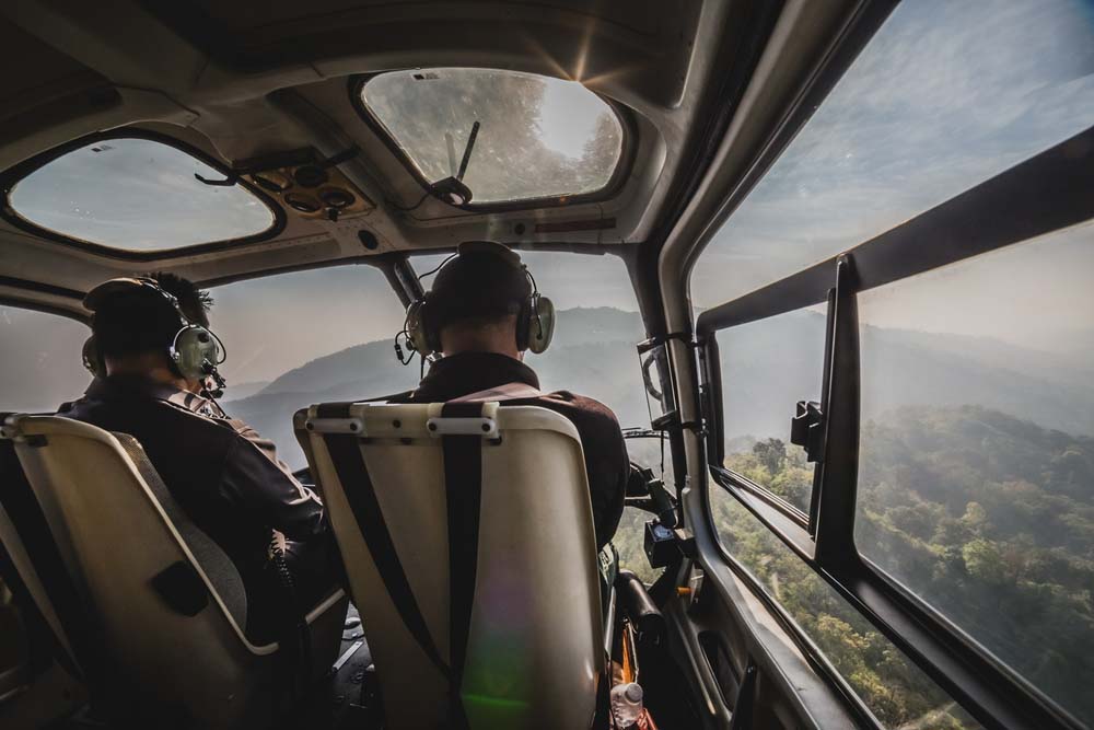 A view of the cockpit of a helicopter from behind the pilot and co-pilot.