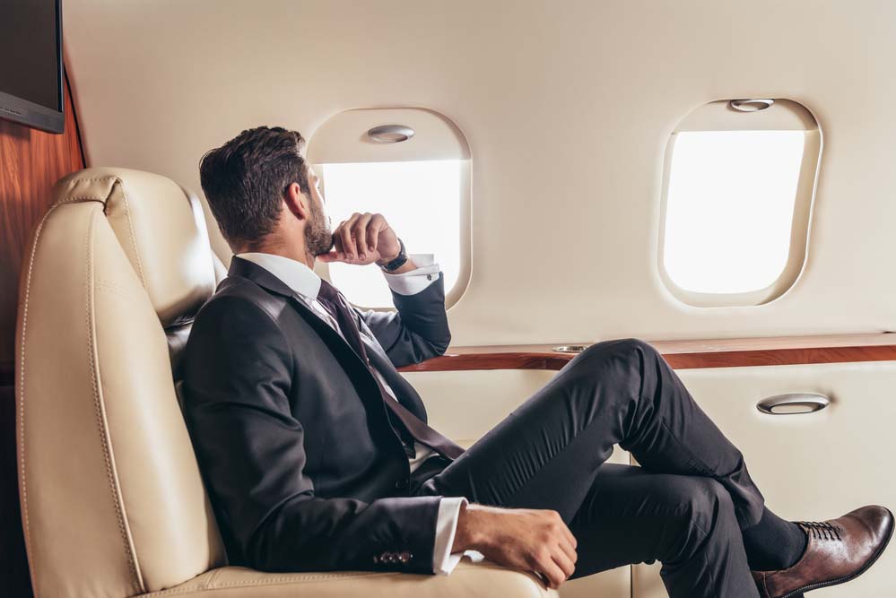 a passenger on a private jet wearing a black business suit